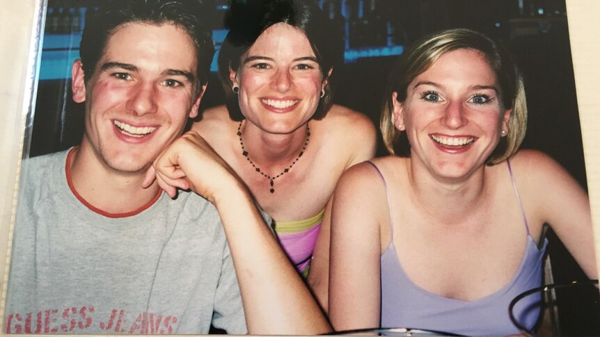 Three siblings photographed smiling next to each other