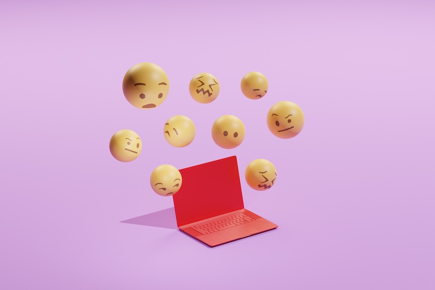 A pink background with a red laptop and yellow emoticon faces flying around the edges of the screen