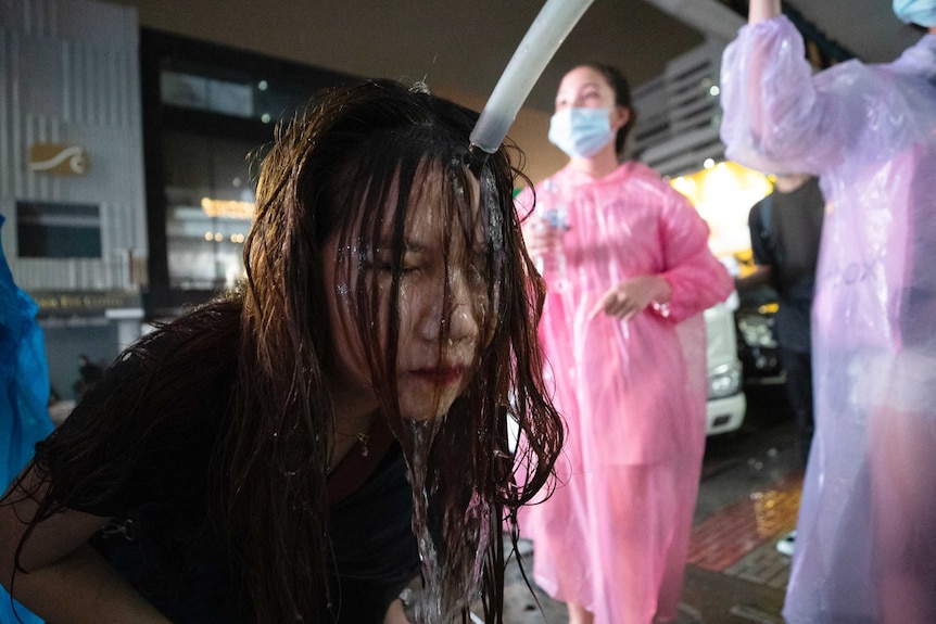 A Thai demonstrator washes her face with water after police water canons dispersed them.