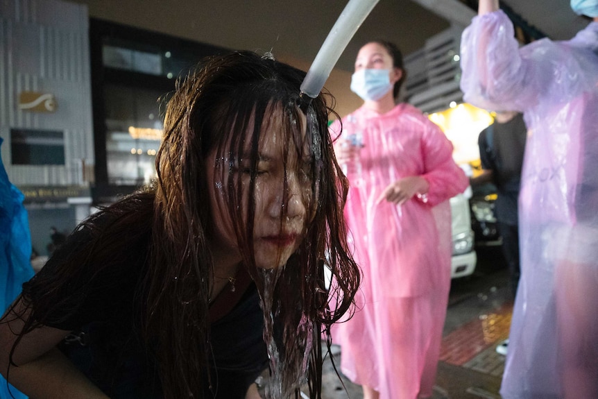 A Thai demonstrator washes her face with water after police water cannons dispersed them.