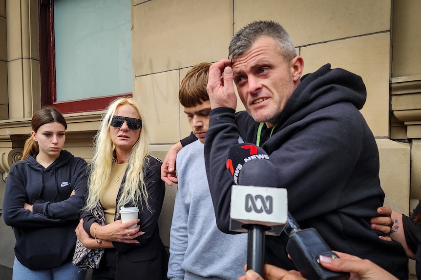 An emotional Bryan Beattie standing with family and friends outside court