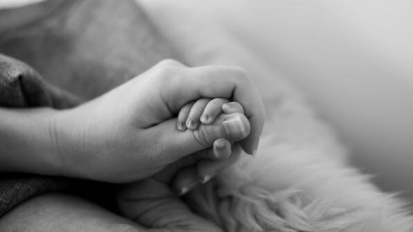 Black and white picture of a mother holding a baby's hand 