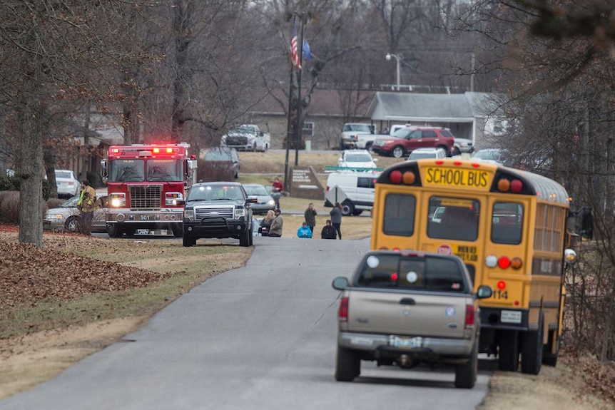 A fire truck and school bus are seen among other vehicles on the side of a road.