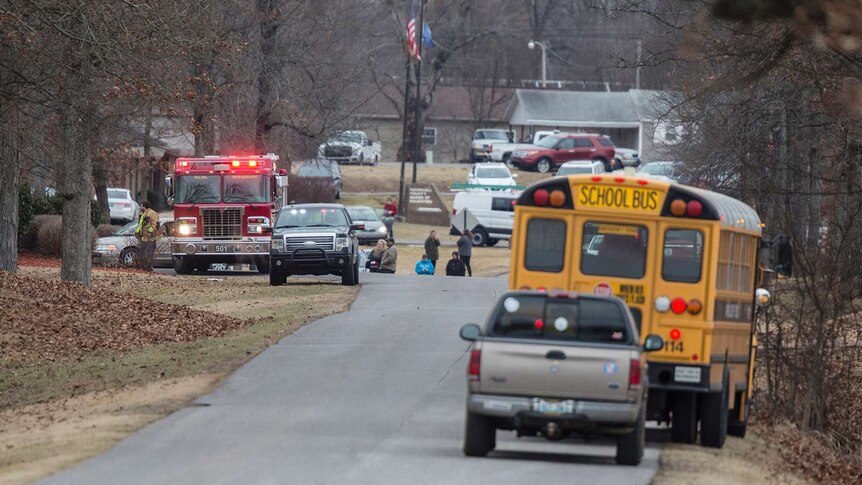 A fire truck and school bus are seen among other vehicles on the side of a road.