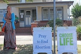A woman stands outside of the Albury clinic protesting against abortion.