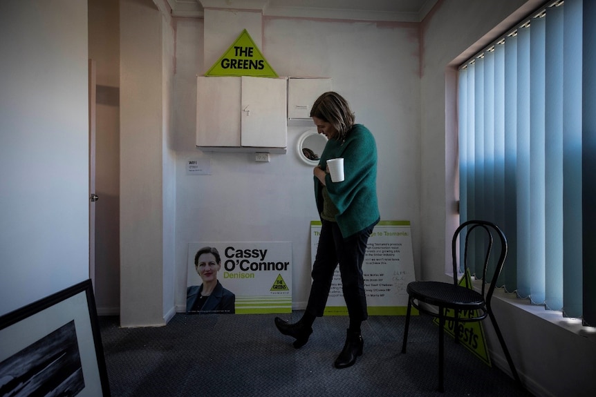 Cassy O'Connor looks at an election corflute with her name and image on it.