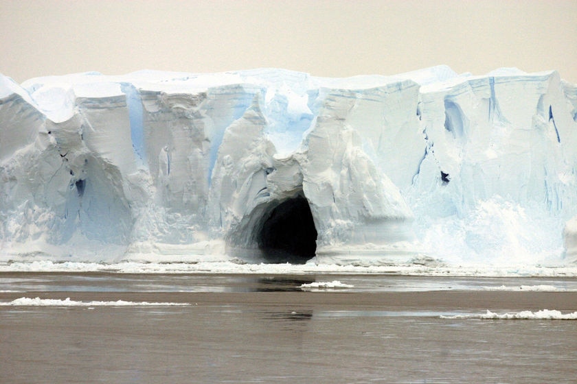 An ice cave yawns from the pit of a sagging iceberg in Antarctica