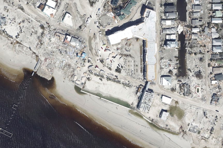 A satellite image show damaged houses along a coast line.