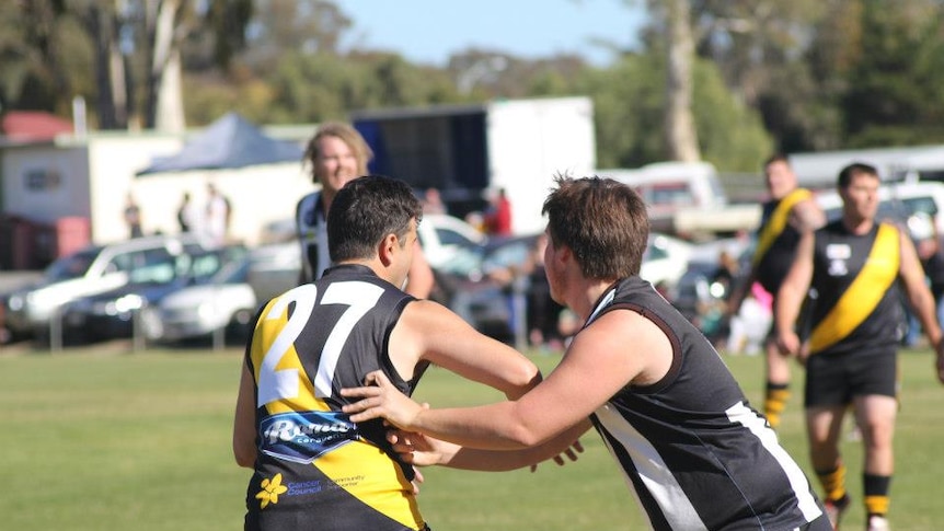 Two footy players get ready for a contested mark at a country footy game