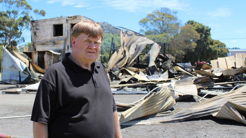 The burned remains of the building. A man is standing in front looking unhappy.