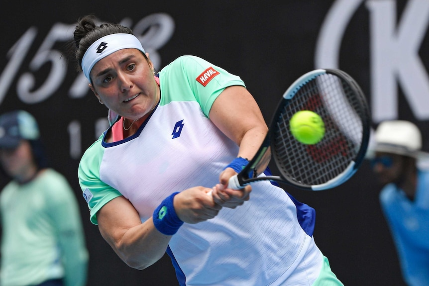A female tennis player plays a double-fisted backhand at the Australian Open.