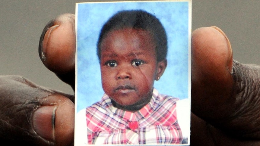 A relative holds a photo of Ayen Chol, 4, who was killed by a pitbull terrier.