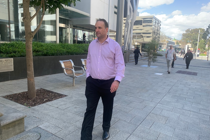 A man in a pink shirt is walking