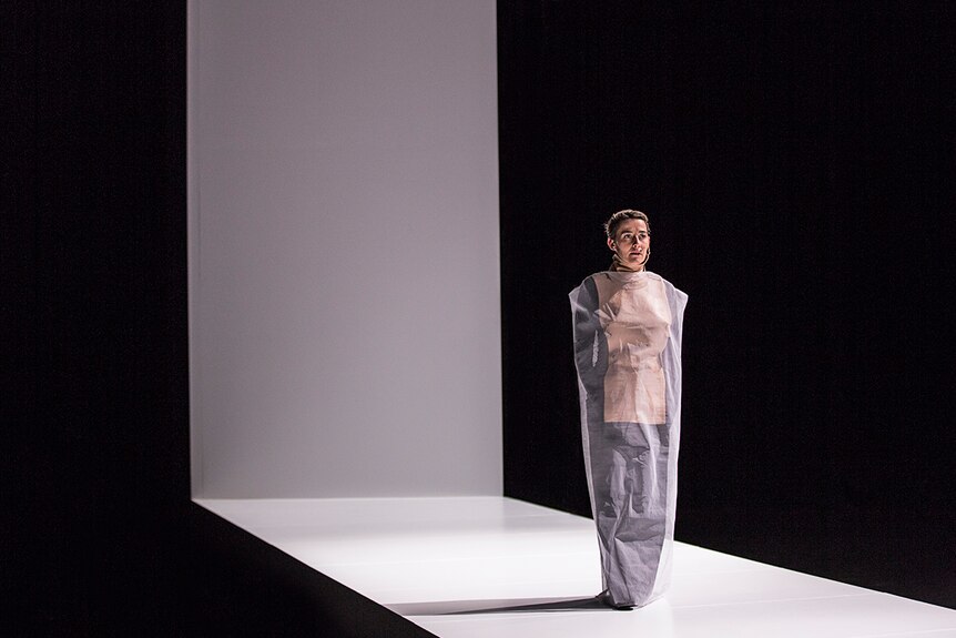 Performer Jane Sheldon stands on dramatic L-shaped white stage during The Howling Girls rehearsals.