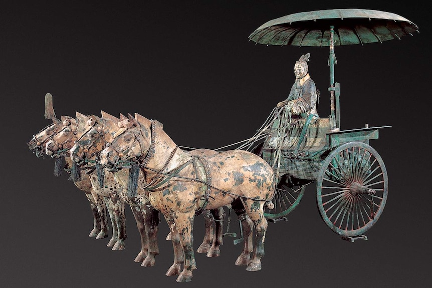 Bronze sculpture of chariot drawn by four horses, with ancient chinese warrior in carriage with umbrella above.