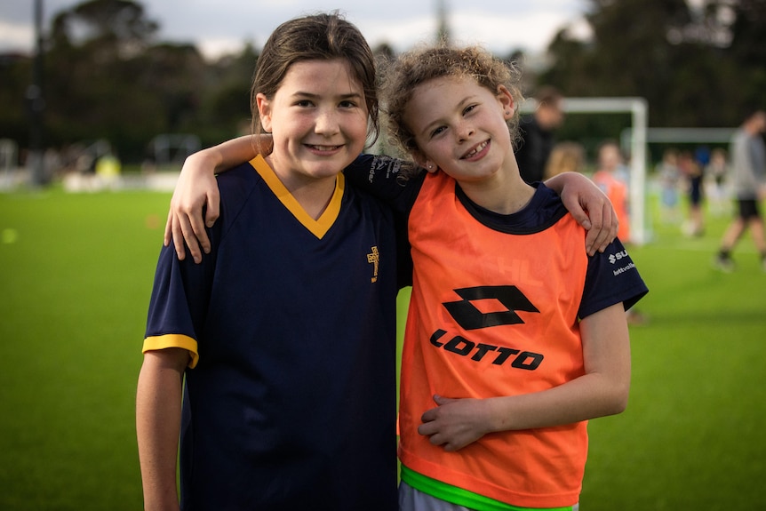 Two young female Football Ferns fans pose for a photo at a training session in New Zealand.