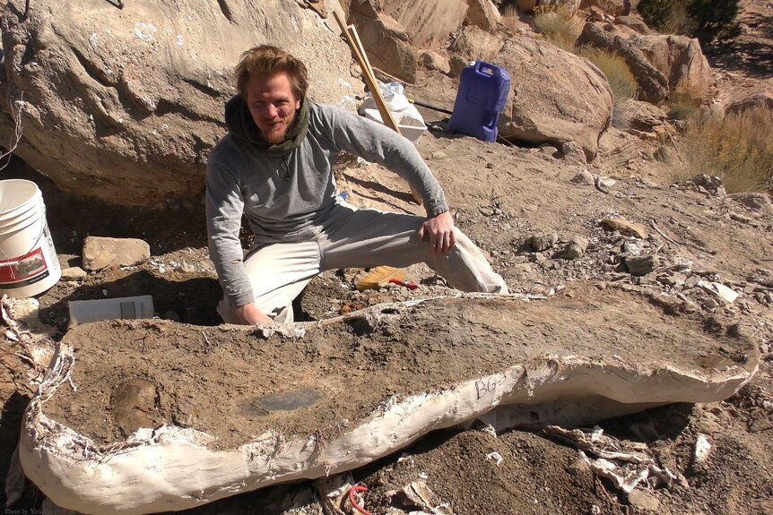 Palaeoartist Brian Engh with dinosaur arm bone in Utah desert