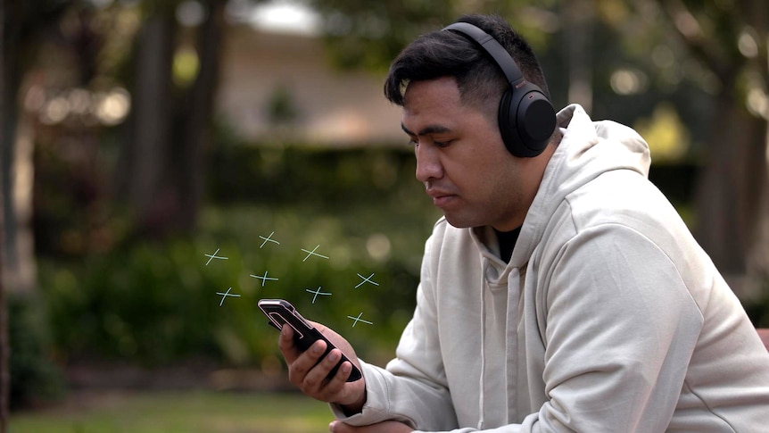 Paniora looks at his phone while sitting outside. Illustrated crosses surround his phone which has a pink edge drawn around it.