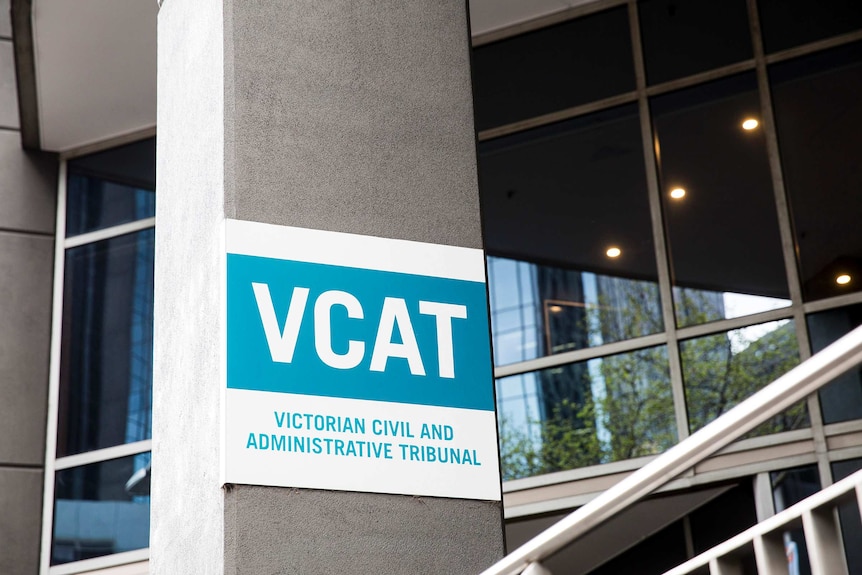 A blue and white sign is attached to a concrete pillar