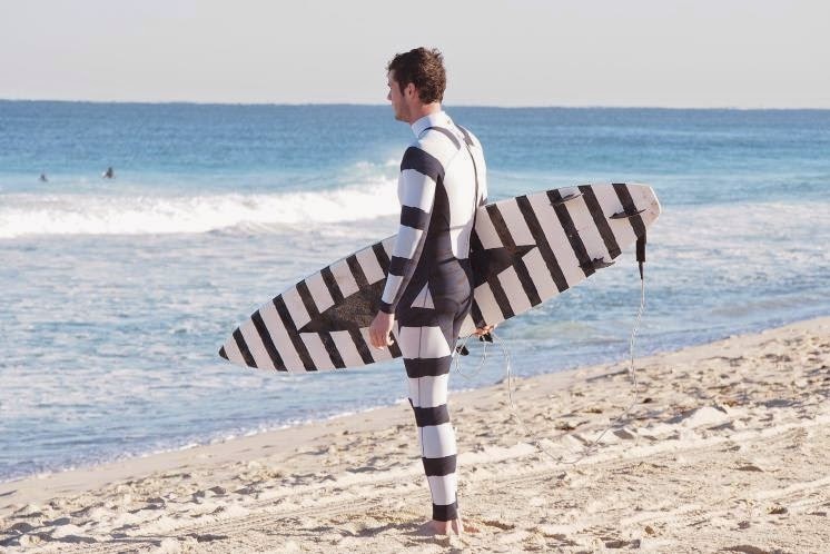 A surfer with a black and white wetsuit and board.