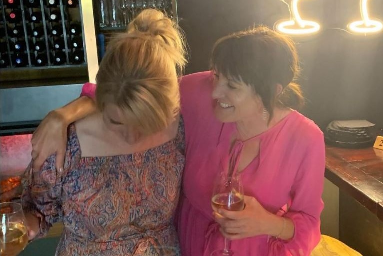 Two women laugh together in a bar for a story on supporting single parents