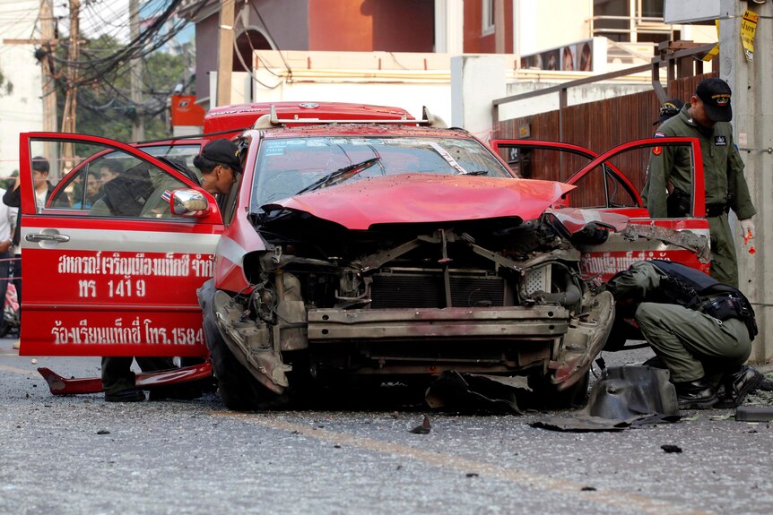 Policemen inspect a taxi damaged in an explosion in central Bangkok.