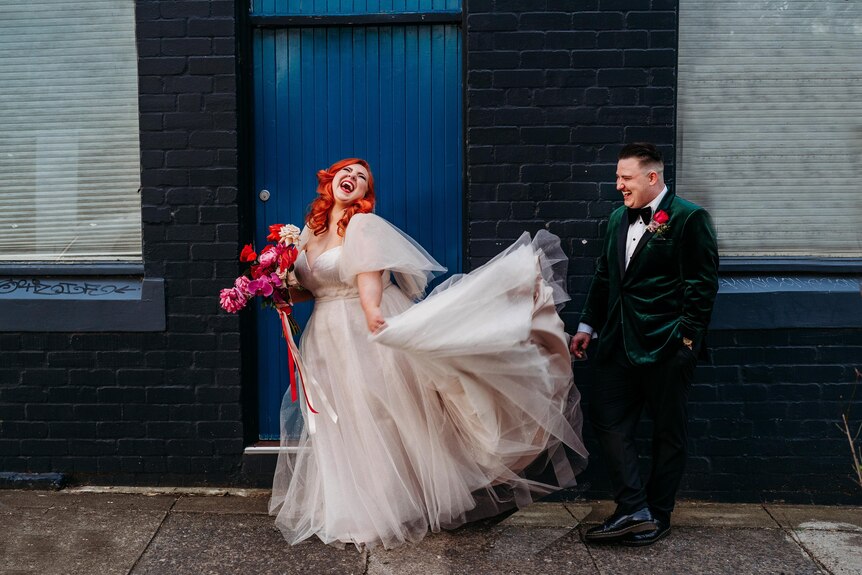 Couple in wedding outfits stands in the doorway 