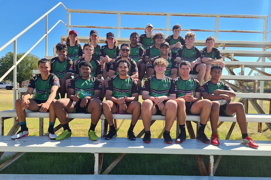 A group of rugby players sitting on bleachers after training session