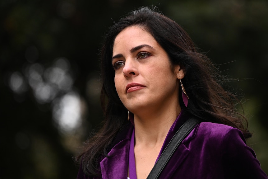 Moira Deeming appears serious as she walks through the parliament carpark, wearing a purple blazer.