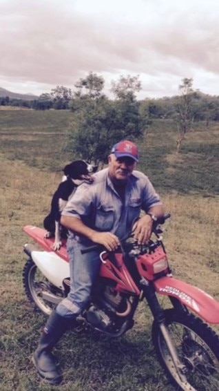 Old photo of man on motorbike with dog on back, in paddock
