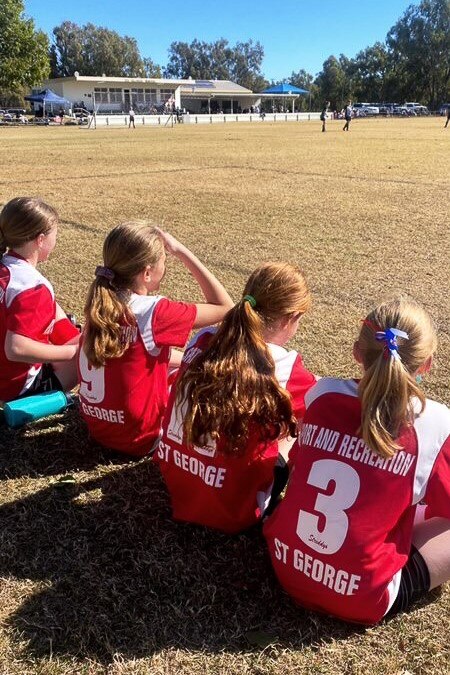 four soccer players sit on the sidelines
