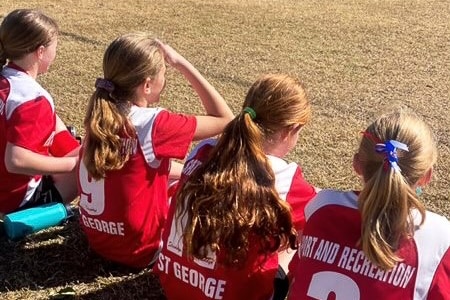 four soccer players sit on the sidelines