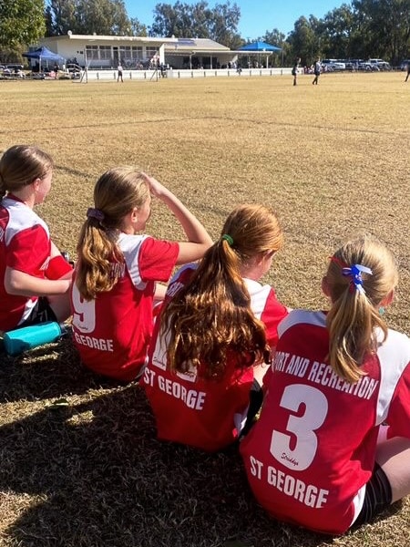 four soccer players sit on the sidelines