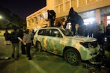 Libyan protesters destroy a car
