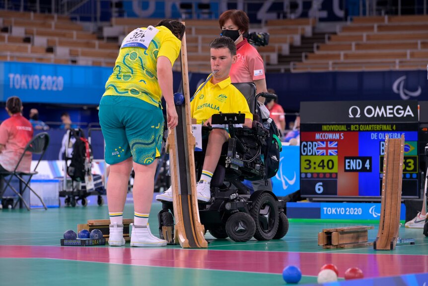 Boccia athlete Daniel Michel prepares a ball on a ramp using a pointer held in his mouth. he is in a wheelchair