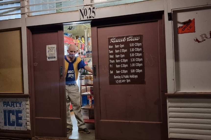 A man closing the door of an old shop.