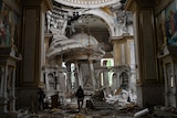 A man walks in a heavily damaged cathedral