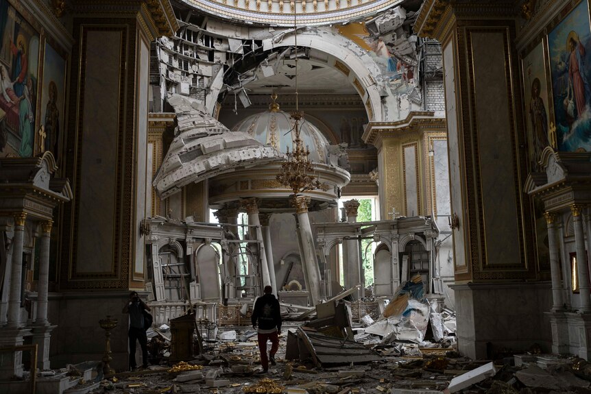 A man walks in a heavily damaged cathedral