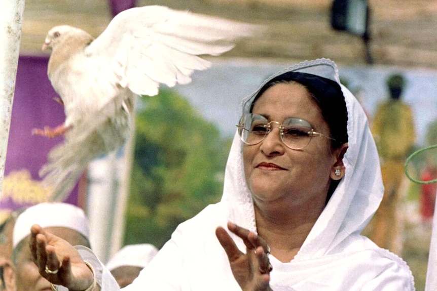 A woman in a white veil releases a white pigeon 