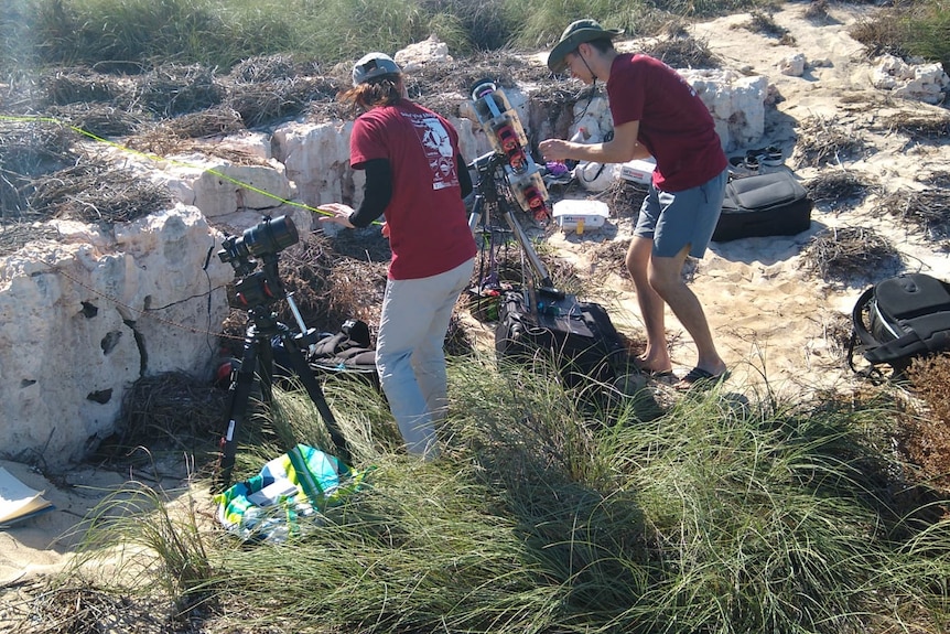 A group of people set up photographic equipment on a remote island.
