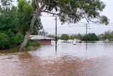 A home partially submerged in brown floodwaters