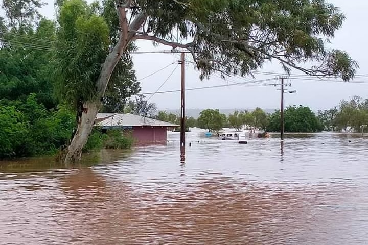 A home partially submerged in brown floodwaters