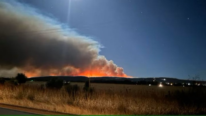 Landscape photo of fire burning in distance at night