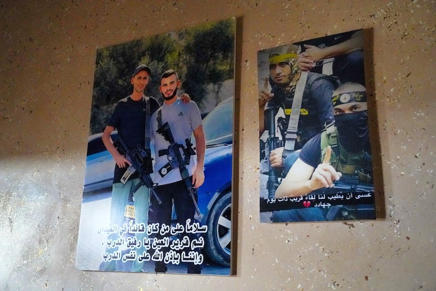 Two posters on a wall featuring men smiling, and carrying guns