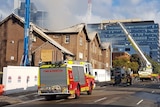 Four fire engines outside a school in Sydney hosing the roof as smoke rises
