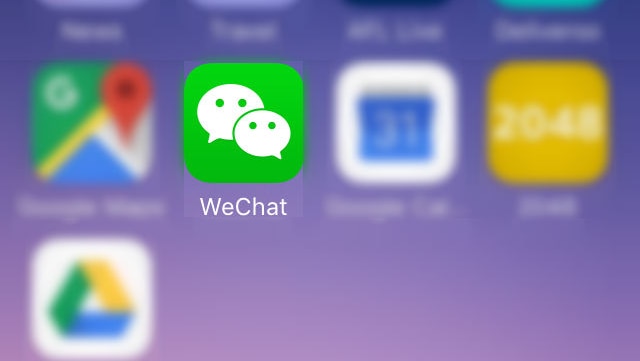 A green icon with two speech bubbles, symbolising social media platform WeChat, is highlighted on a mobile phone screen.