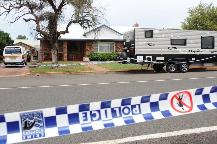 Brick home with caravan surrounded by police tape.