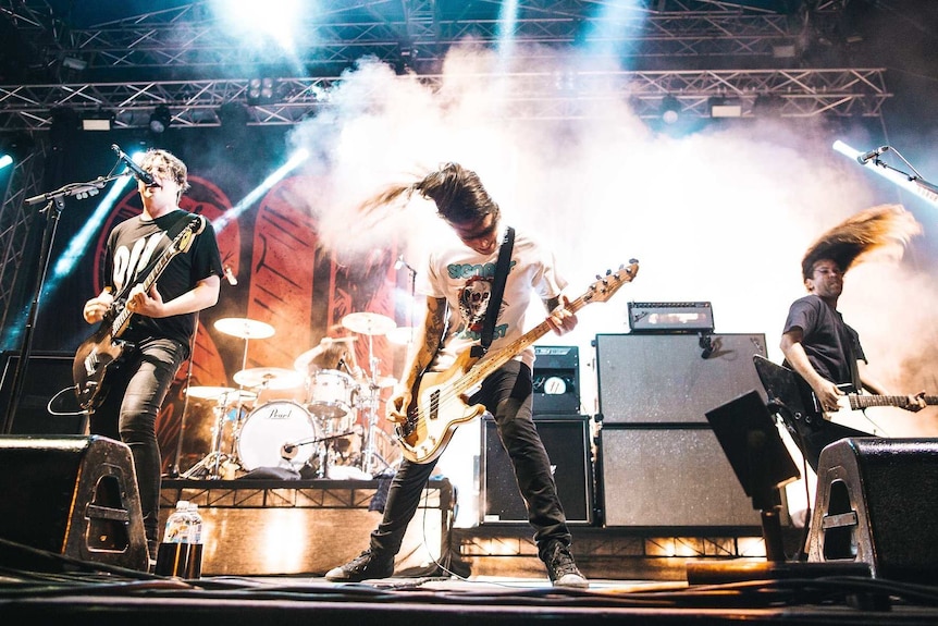 Three members of Violent Soho on stage mid-set, head banging.