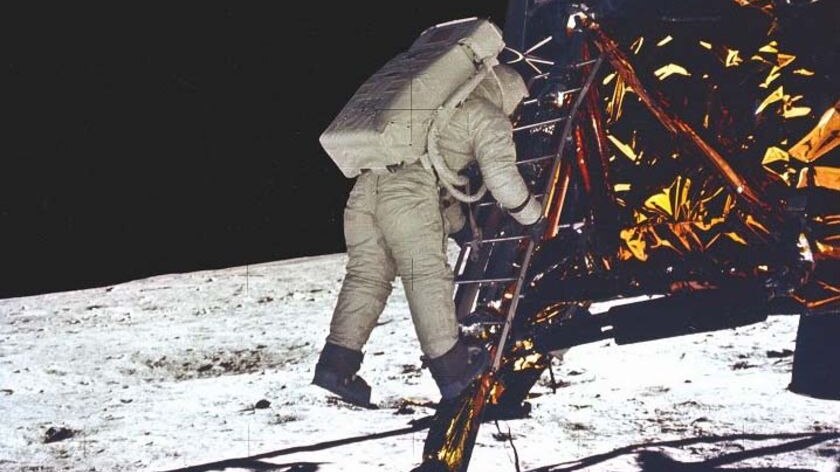An astronaught climbs down a ladder from The Eagle spacecraft and steps towards the moon.