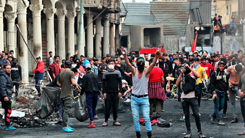 Anti-government protesters gather on Rasheed Street during ongoing protests in Baghdad. Many are masked.